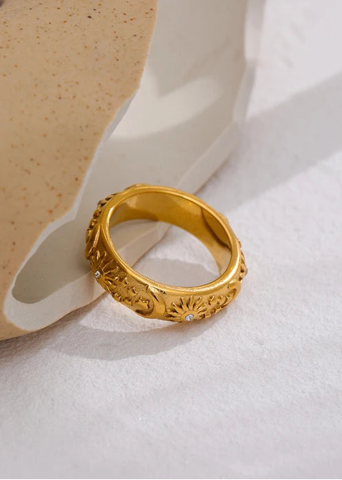 Gold ring with intricate design on a white surface