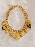 Gold charm bracelet with heart-shaped pendants on a textured beige background