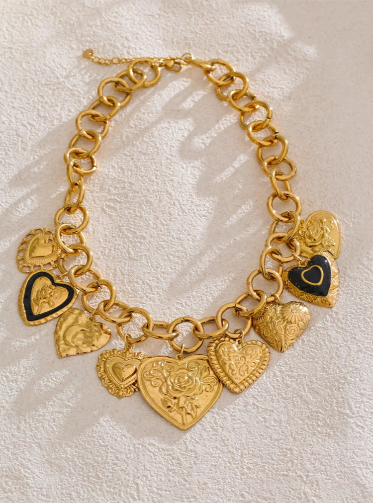 Gold charm bracelet with heart-shaped pendants on a textured beige background