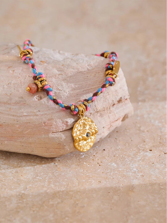 Bracelet with colorful beads and a gold charm on a stone surface