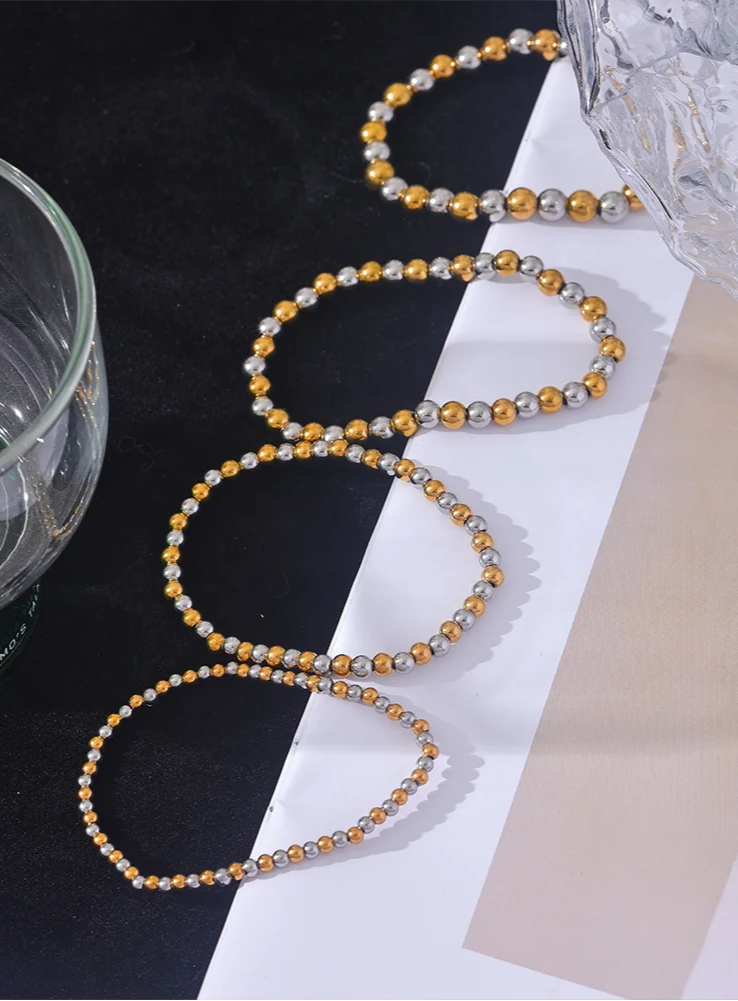 Gold and silver beaded necklace on a black and white surface