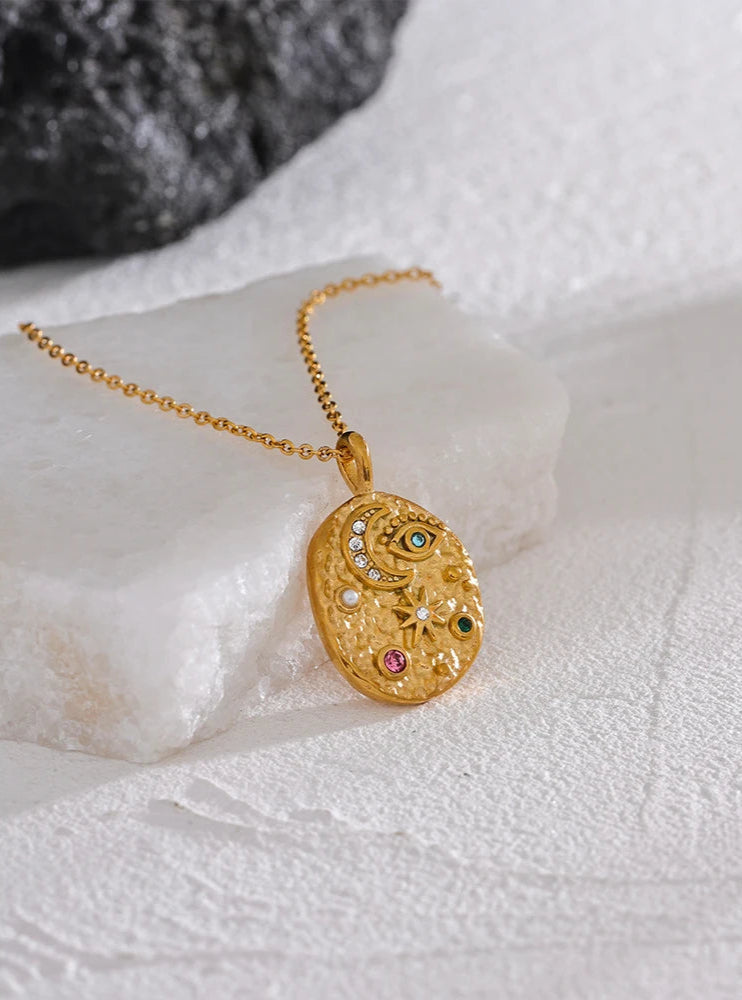 Gold necklace with a decorative pendant on a textured white surface