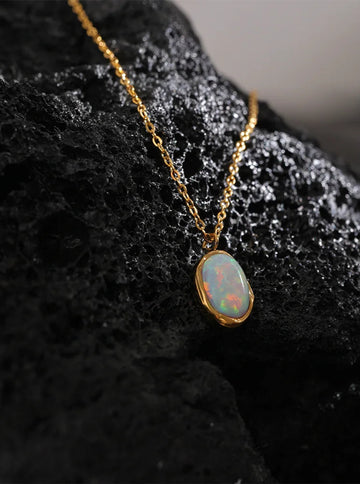 Opal pendant necklace on a dark textured surface