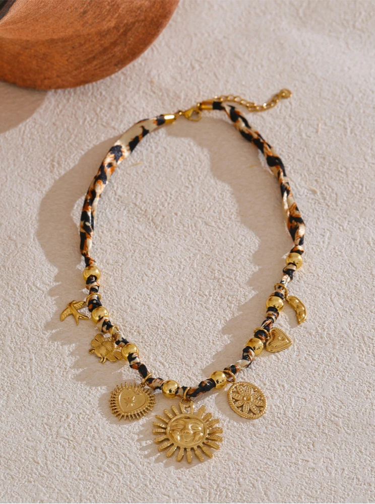 Leopard print Necklace with gold and black beads and charms on a light background