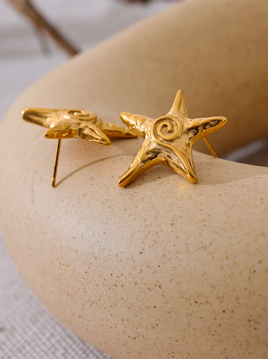 Gold star-shaped earring on a beige surface