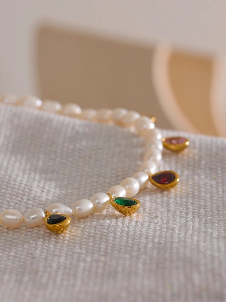 Pearl bracelet with gemstone accents on a textured surface