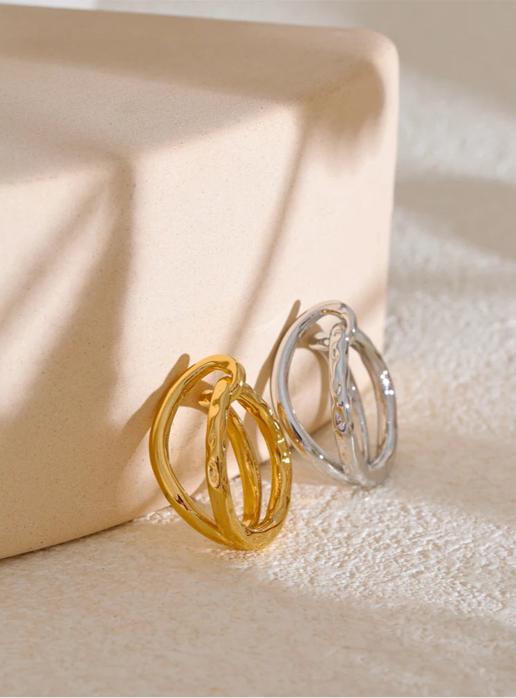Gold and silver hoop ring on a textured beige surface
