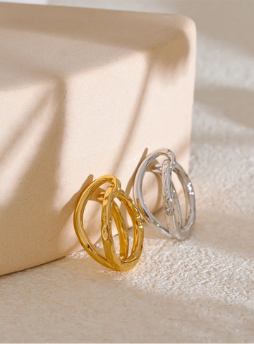 Gold and silver hoop ring on a textured beige surface