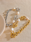 Two pearl-encrusted bracelets, one gold and one silver, on a beige surface.
