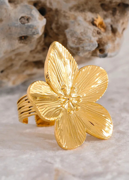 Gold flower-shaped ring on a textured surface